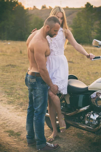 Liebespaar auf einem Motorrad in einem Feld — Stockfoto
