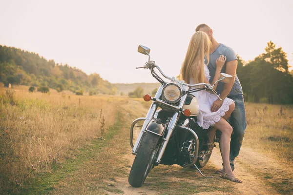 Loving couple on a motorcycle in a field — Stock Photo, Image