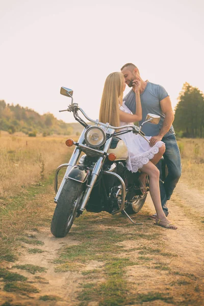 Loving couple on a motorcycle in a field — Stock Photo, Image