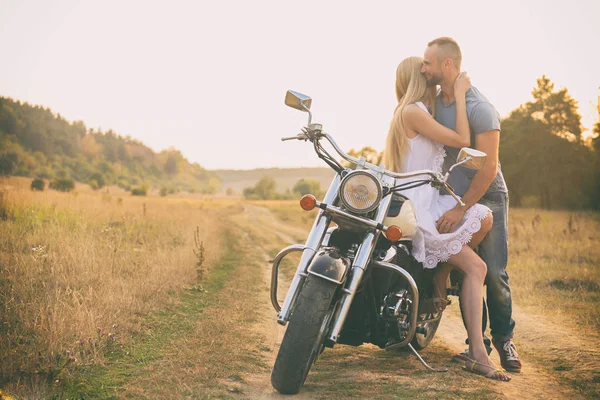 Casal amoroso em uma motocicleta em um campo — Fotografia de Stock
