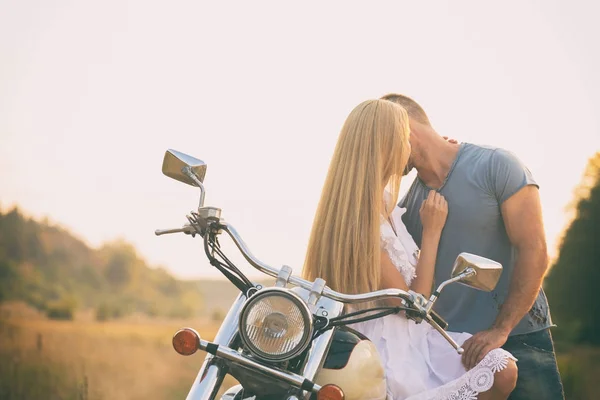 Loving couple on a motorcycle in a field — Stock Photo, Image