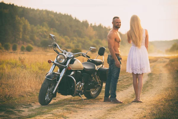 Lovers on a motorcycle in a field — Stock Photo, Image