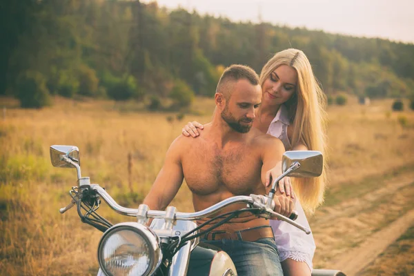 Lovers on a motorcycle in a field — Stock Photo, Image