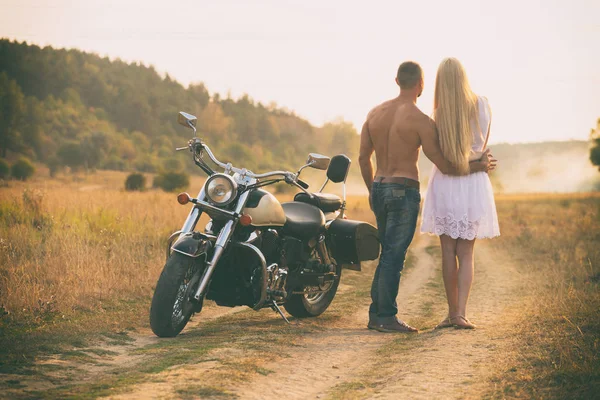 Amantes em uma motocicleta em um campo — Fotografia de Stock