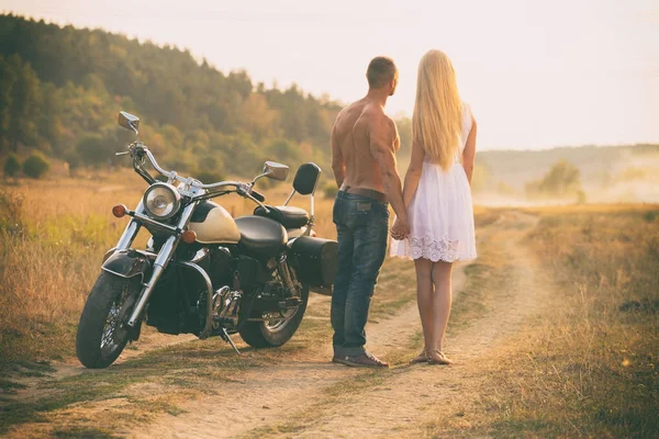 Lovers on a motorcycle in a field — Stock Photo, Image