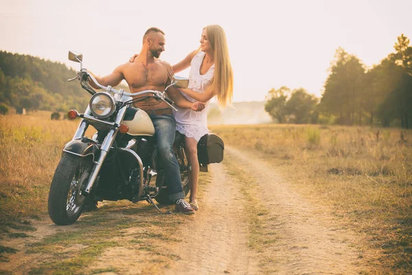 Amantes em uma motocicleta em um campo — Fotografia de Stock