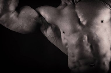 Karanlık bir arka plan üzerinde vücut geliştirmeci.