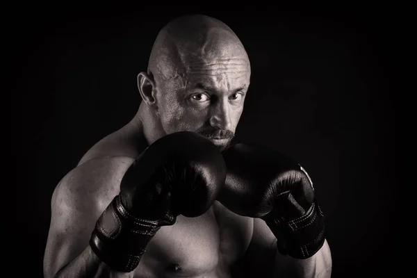 Een man met een schitterende gespierd lichaam op een zwarte achtergrond — Stockfoto