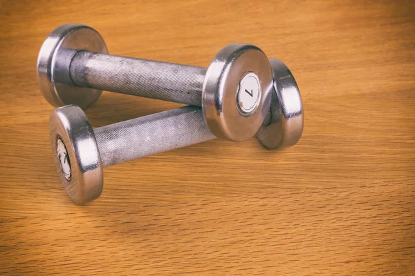 Dumbbells and gloves on a wooden background. — Stock Photo, Image