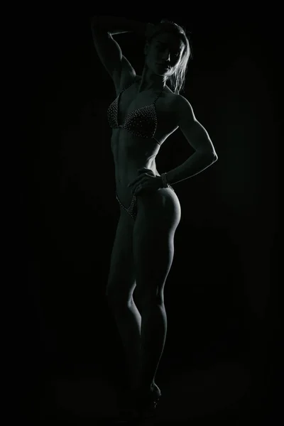 Athletisches Mädchen auf dunklem Hintergrund. — Stockfoto