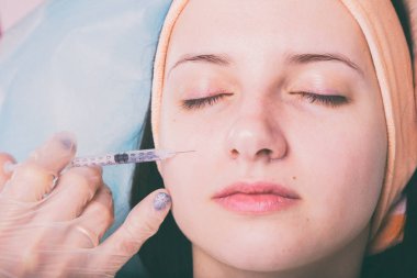 Kozmetik enjeksiyon spa salonda. Güzellik uzmanı hastanın yüz içine enjeksiyon yapar.