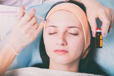Kozmetik enjeksiyon spa salonda. Güzellik uzmanı hastanın yüz içine enjeksiyon yapar.