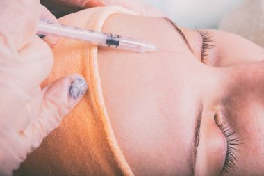 Kozmetik enjeksiyon spa salonda. Güzellik uzmanı hastanın yüz içine enjeksiyon yapar.