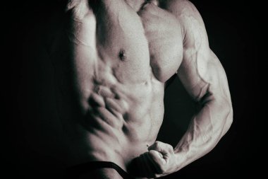 Karanlık bir arka plan üzerinde vücut geliştirmeci.