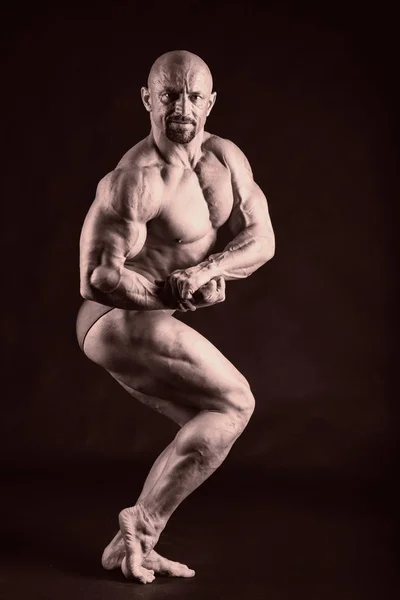 Bodybuilder on a dark background. — Stock Photo, Image