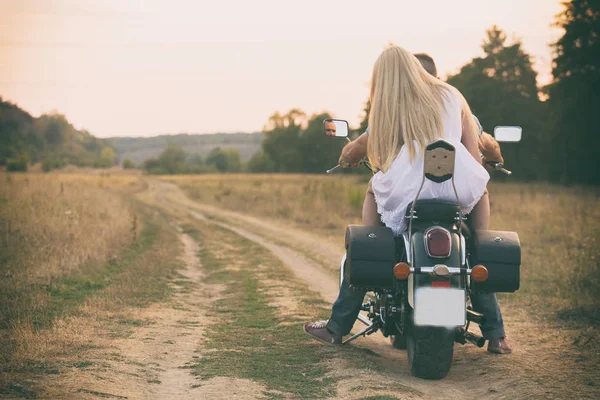 Young couple on a motorcycle in the field
