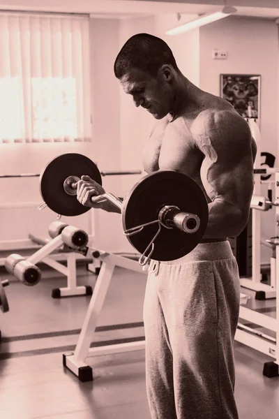Um homem com um exercício de sino no bíceps — Fotografia de Stock