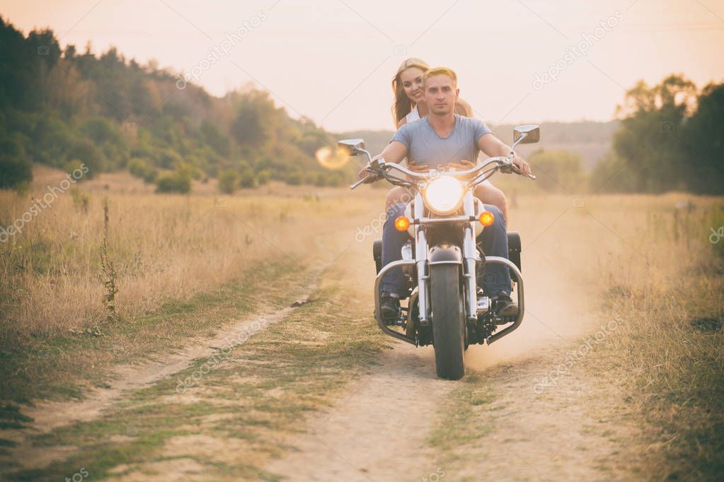 Young couple on a motorcycle in the field