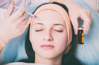 Kozmetik enjeksiyon spa salonda. Güzellik uzmanı hastanın yüz içine enjeksiyon yapar.