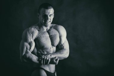 Karanlık bir arka plan üzerinde vücut geliştirmeci.