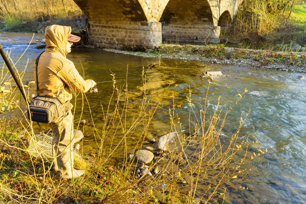 Pescatore cattura una trota su un fiume di montagna — Foto Stock