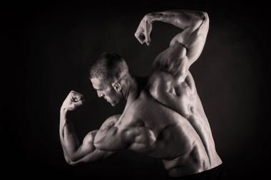 Karanlık bir arka plan üzerinde vücut geliştirmeci.