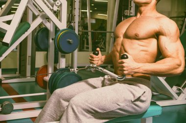 Spor salonunda egzersiz yapan kaslı bir adam.