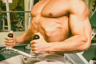 Spor salonunda egzersiz yapan kaslı bir adam.