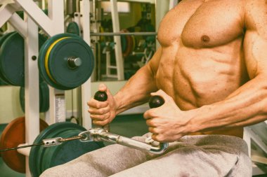 Spor salonunda egzersiz yapan kaslı bir adam.