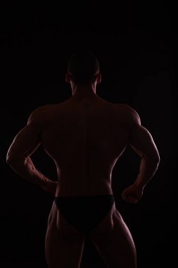 Siyah arka planda poz veren kaslı ve formda genç vücut geliştirici fitness erkek modeli