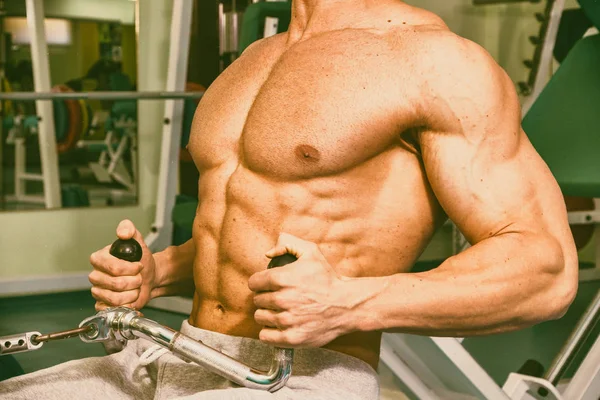 Homem musculoso exercitando-se no ginásio fazendo exercícios — Fotografia de Stock