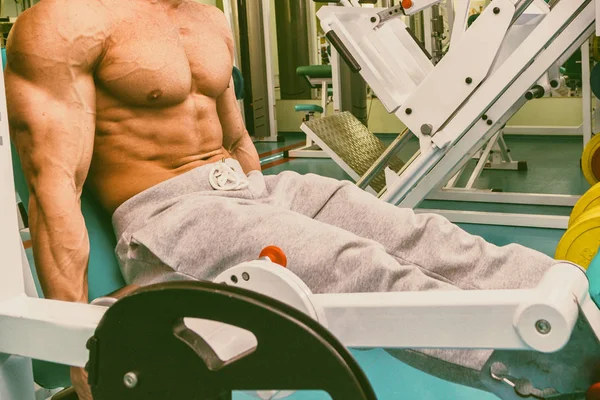 Мускулистый человек работает в спортзале, делая упражнения — стоковое фото