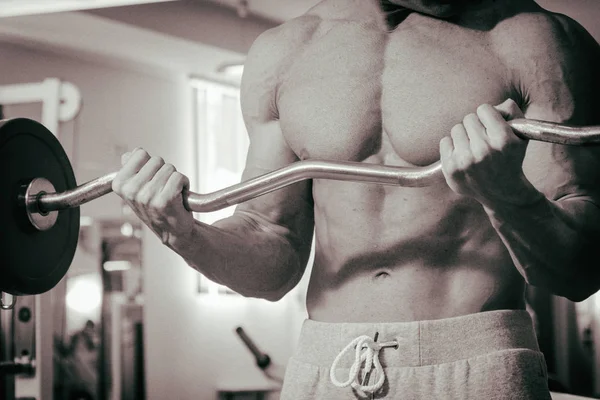 Homem musculoso exercitando-se no ginásio fazendo exercícios — Fotografia de Stock