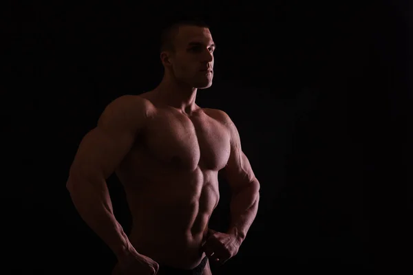 筋肉質とフィット若いですボディビルダーフィットネス男性モデルポーズ上の黒の背景 — ストック写真