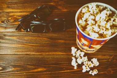 Patlamış mısır ve ahşap arka plan üzerinde 3d film izlemek için gözlük. Tonda fotoğraf