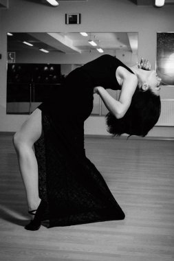 Siyah elbiseli bir kız salonda dans ediyor