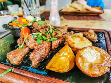 Biftek ve patates arka planda.