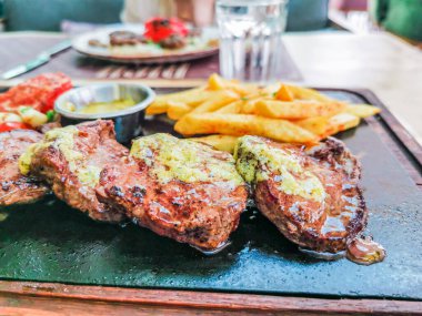 Biftek ve patates arka planda.