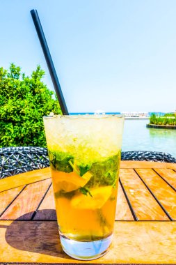 Mojito kokteyli deniz arka planında bir masada açık hava seyahatinde.