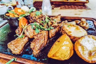 Biftek ve patates arka planda.