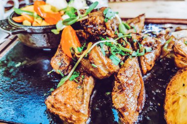 Biftek ve patates arka planda.