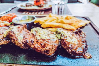 Biftek ve patates arka planda.