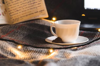  Parlak Noel ışıklarının arka planında çikolata olan küçük bir fincan sıcak çay. Yeni yılın sıcak ve samimi atmosferi.