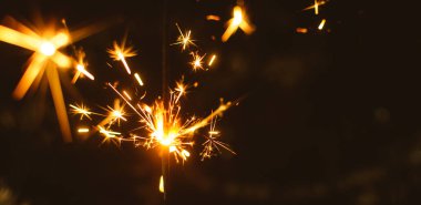 Noel ve Yeni Yıl için kıvılcımlar sıcak renklerde bir tatil arka planında yakın plan, geniş fotoğraf