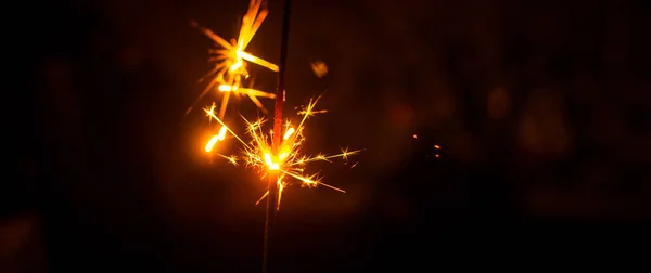 Chispas para Navidad y Año Nuevo de cerca en forma de una pancarta y sobre un fondo negro —  Fotos de Stock