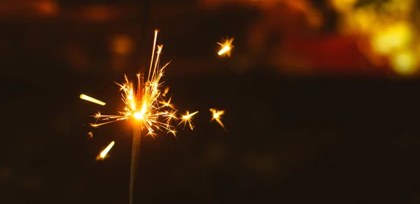 Chispas para Navidad y Año Nuevo de cerca en un fondo de vacaciones en colores cálidos, foto amplia — Foto de Stock