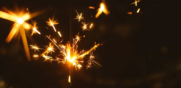 Chispas para Navidad y Año Nuevo de cerca en un fondo de vacaciones en colores cálidos, foto amplia — Foto de Stock