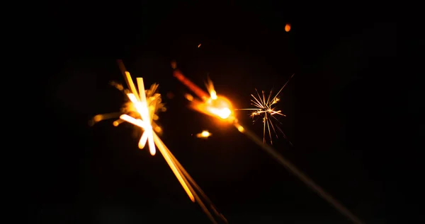 Chispas para Navidad y Año Nuevo de cerca en forma de una pancarta y sobre un fondo negro — Foto de Stock