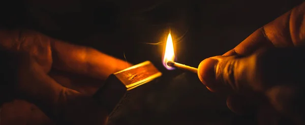 Um fósforo iluminado no escuro nas mãos com uma caixa de fósforos — Fotografia de Stock