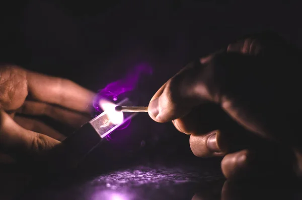 魔法点燃火柴，手中拿着淡淡的彩烟，紫色 — 图库照片